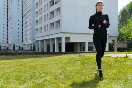 Woman running on the grass in the city