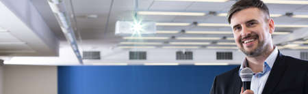 Middle aged handsome smiling businessman leading lecture in auditorium on economy universityの写真素材