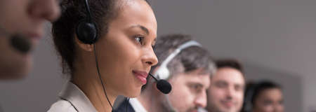Pretty young girl working in call center business. Carefully listening to the client on phone