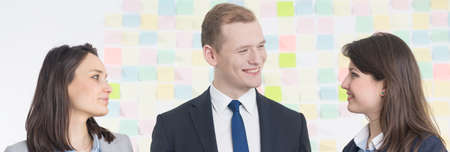 Three colleagues smiling to each other at the officeの写真素材