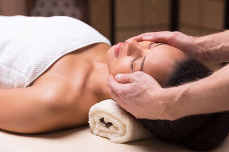 Close-up of young pretty woman relaxing during her face massageの写真素材