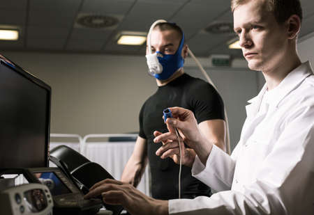 Sportsman in oxygen mask during annual check up and medic in white uniform
