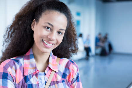 Happy, afroamerican student standing at college building