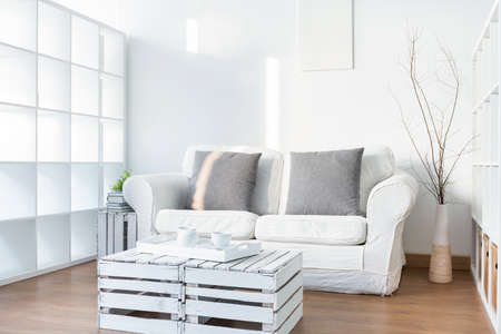 Light living room with sofa and small, wood, handmade tableの写真素材