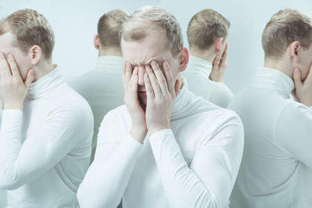 Man with mental problem covering his face with hands, duplicated imageの写真素材