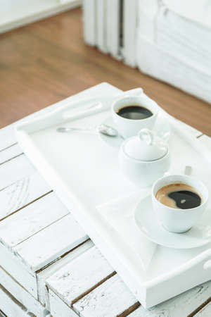 Salver with cups of coffee, standing on handmade, wood, small tableの写真素材