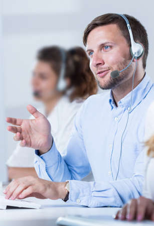 Young handsome man taking with client on headphones