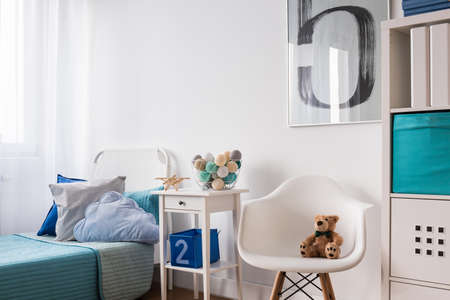 Seaside decorations on nightstand near blue single bed in modern children's roomの写真素材