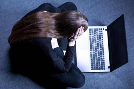 Teenage girl sitting alone in room. Writing with virtual friends in internetの写真素材
