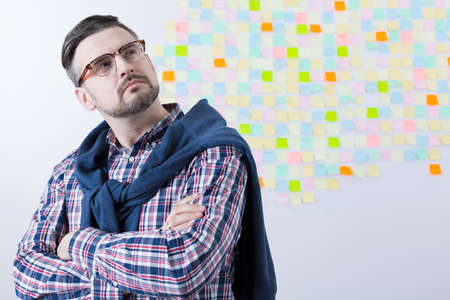 Focused middle aged man ass a leader of business company. Behind him wall with sticky notesの写真素材