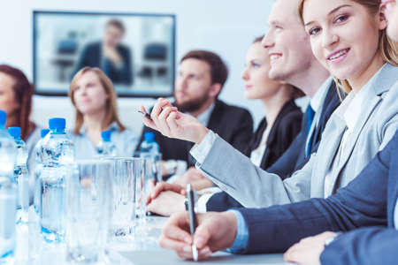 Group of men and women sitting in light office during business meetingの写真素材