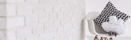 White chair with decorative baby pillow, light interior, panoramaの写真素材