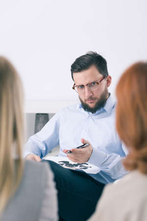 Young handsome psychologist listening his two patients during family therapy sessionの写真素材