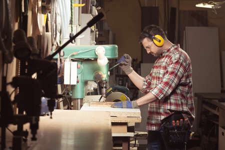 Carpenter working in well equipped workshop.の写真素材