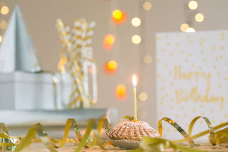 Close-up of muffin with powdered sugar and candle prepared for birthday person. In the background birthday cardの写真素材