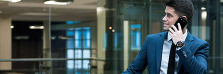 Busy young handsome sales representative working in office. Talking the phone with clientの写真素材