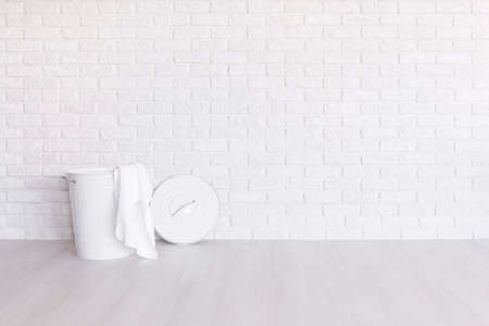 White laundry basket standing in spacious room with light flooring and brick wallの写真素材