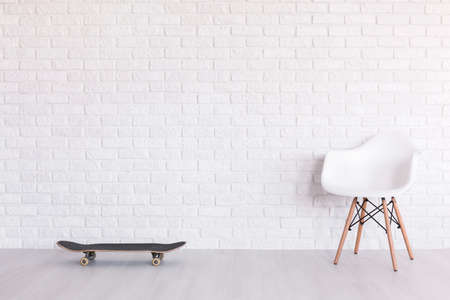 Skateboard and white chair standing in light interior with flooring and white brick wallの写真素材