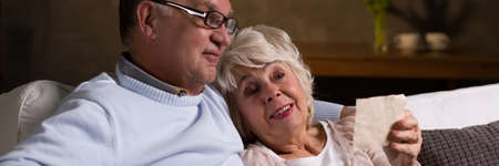 Senior loving couple reminding old good times when they were young. Happy woman holding old photoの写真素材