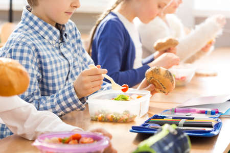 Shot of a group of children eating lunch in a classroomの写真素材