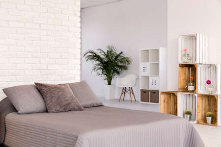White interior with large bed, decorative brick wall and DIY wooden regaleの写真素材