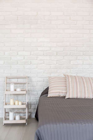 Light bedroom with white brick wall, large bed and handmade nightstandの写真素材