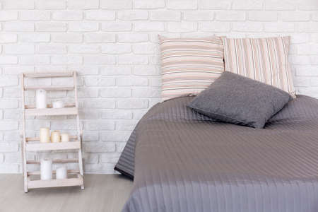White bedroom with decorative brick wall, large bed and handmade nightstandの写真素材