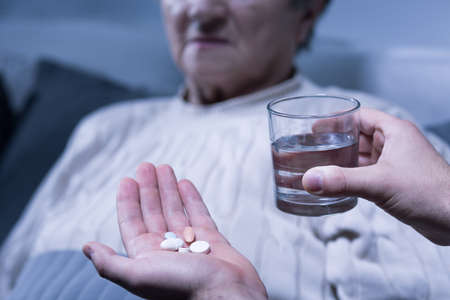 Cropped picture of a person holding some pills and a glass of waterの写真素材