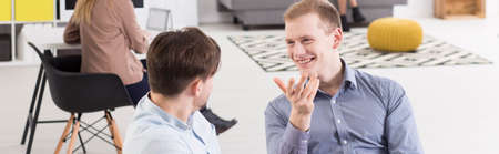 Panorama of two colleagues in a modern office, smiling and talking in a relaxed pose