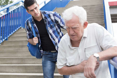 Man giving aid to senior walking downstairsの写真素材