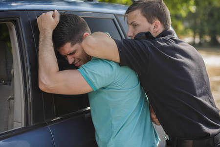 Strong policeman is holding young and dangerous driverの写真素材