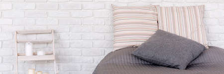Shot of a bed and a brick wall in a cosy modern bedroomの写真素材
