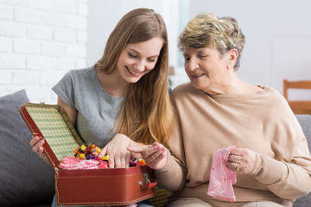 Grandmother and granddaughter spending time together, sitting in cozy home interiorの写真素材