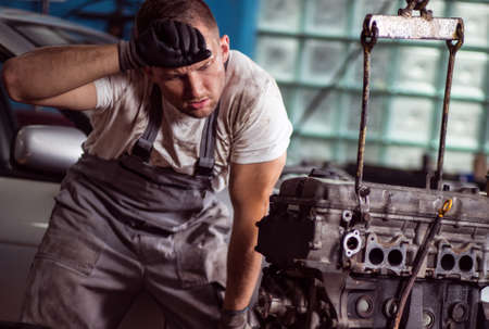 Young car mechanic is very tired at his workの写真素材