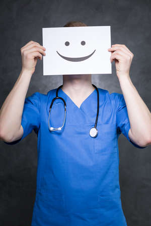 Shot of a young doctor holding a paper with a happy face on itの写真素材