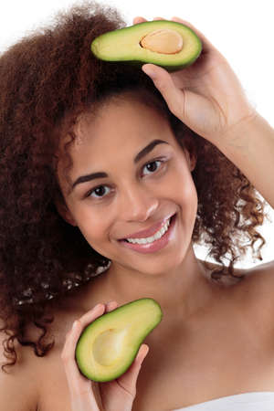 Portrait of an afroamerican woman holding two pieces of an avocado, white background