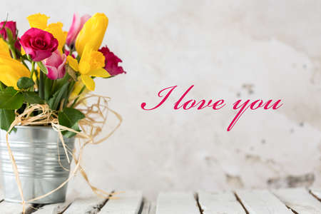 Shot of a colorful bunch of flowers and 'I love you' writing on the wallの写真素材