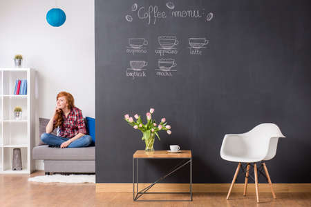 Shot of a pretty young woman sitting on a sofa in a modern apartmentの写真素材