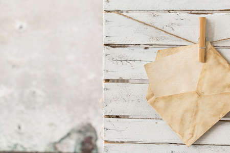 Card in yellowed envelope hanging on a string, wood planks in the backgroundの写真素材