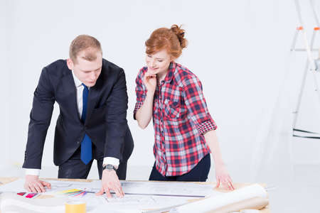 Estate agent showing some plans to a cheerful woman inside a room that is being renovatedの写真素材