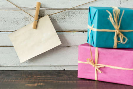 Wrapped gifts and card hanging on a string, white, rustical planks in the backgroundの写真素材