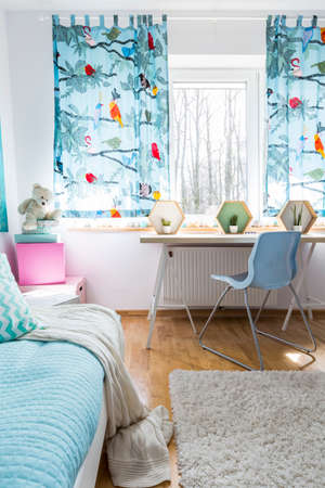 Shot of a very bright room with bed, desk and window overlooking winter forestの写真素材