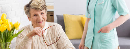 Shot of a smiling elderly woman and a doctor standing next to herの写真素材