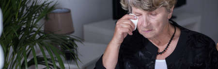 Miserable elderly woman crying and wiping the tears awayの写真素材