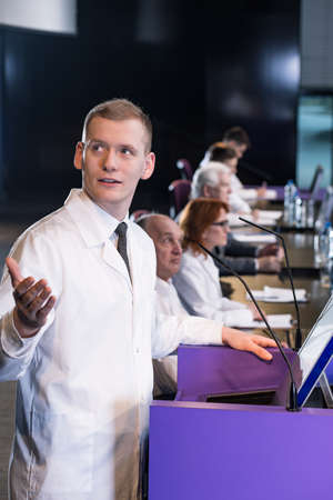 Young male reader giving presentation at lectern indoors