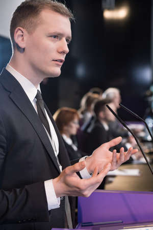 Young businessman at podium giving press conference