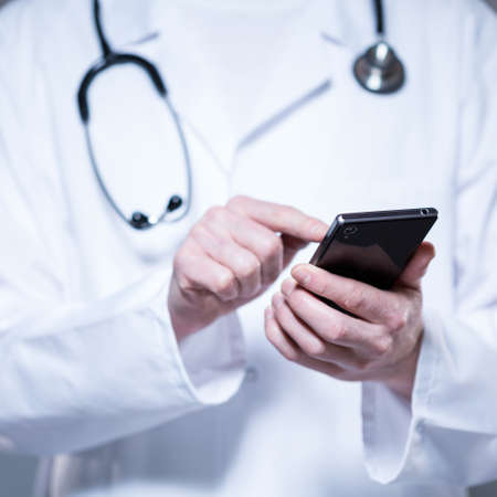Male doctor hands using mobile phone, horizontalの写真素材
