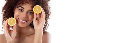 Smiling pretty young woman with dark smooth skin on a white background holding halves of juicy orangesの写真素材