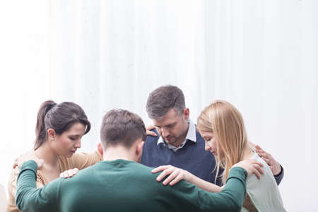 Group of people holding each other at the shoulders forming circle