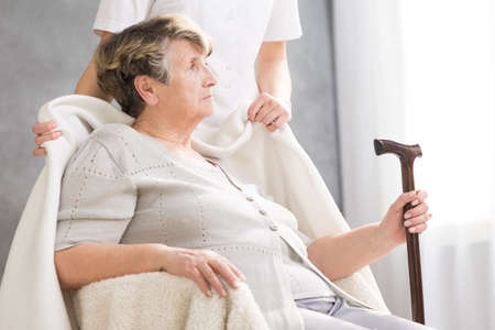 Senior woman with a walking stick and her carer